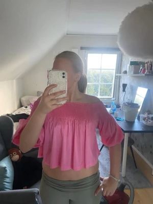 Rosa offshoulder croppad topp - Säljer en söt rosa offshoulder topp med croppad passform och vida ärmar. Aldrig använt och är i mycket bra skick. Säljs inte längre och är perfekt till sommaren!