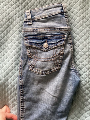 Ljusblå jeans från Perfect Jeans - Snygga ljusblå jeans från Perfect Jeans med klassisk femficksdesign och coola kontrastsömmar. Bakfickan har lock och knappdetalj som ger extra stil. Jeansen har normal midja och är tillverkade i mjukt denimtyg.