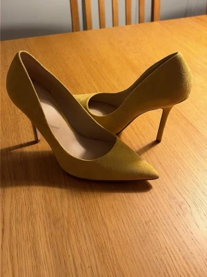 Gula pumps i mocka från Aldo - Snygga gula pumps från Aldo med spetsig tå och smal klack. Skorna är tillverkade i mocka och har en klassisk, elegant siluett som ger en trendig touch till din outfit. Perfekta för dig som vill sticka ut med färg och stil. orginalkartong finns. Endast testade.