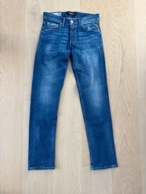 Replay blåa jeans - Snygga blå jeans från Replay med raka ben och klassisk femficksmodell. Jeansen har en tvättad look med ljusare partier och silverfärgade detaljer på knappar och nitar. 