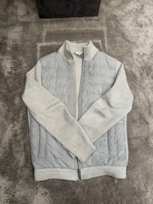 Ljusgrå cardigan från Reiss - Snygg ljusgrå cardigan med quiltad front och rygg samt stickade ärmar. Perfekt nu mot våren. Pris går att diskutera vid smidig affär!