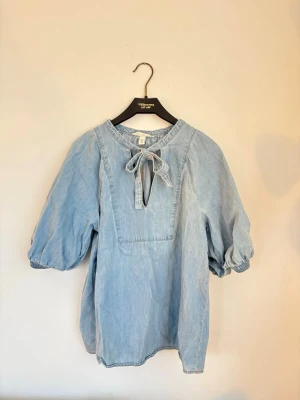 Ljusblå denimblus från H&M - Trendig ljusblå blus i denim från H&M. Super fin till sommaren. Storlek S.