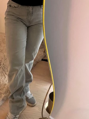 Ljusgrå raka jeans - Säljer ett par ljusblå jeans med rak passform och hög midja. Jeansen har klassiska fem fickor och är tillverkade i ett mjukt denimtyg. Perfekta för en avslappnad och trendig look.