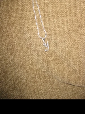 Silverfärgat halsband med bokstavshänge från Swarovski  - Snyggt halsband i silverfärg med ett hänge format som bokstaven 'Y'. Kedjan är tunn och vriden, vilket ger ett stilrent och modernt intryck. Perfekt accessoar för dig som vill ha något personligt och enkelt.