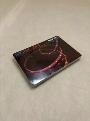 LED Strip Lights från NBUFF - Säljer en förpackning LED Strip Lights från NBUFF. Perfekt för att skapa cool belysning i rummet eller bakom TV:n. Kommer i en platt, svart förpackning med färgglad design. Passar till dig som vill ha smart och flexibel belysning.