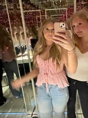 Rosa volangtop  - Supersöt rosa linnetopp från New Yorker med tunna axelband, volangdetaljer och knyt framtill. Toppen har en lätt ribbad struktur och är perfekt för sommarens alla tillfällen. Luftig och feminin design som ger en romantisk vibe. Storlek M men passar för S 