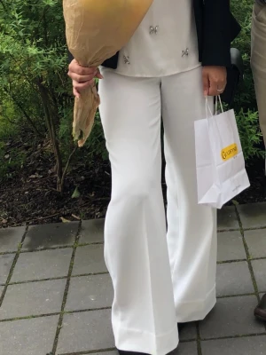 Vita utsvängda kostymbyxor - Säljer ett par vita kostymbyxor med hög midja och utsvängda ben. Byxorna har en snygg, klassisk look och är perfekta för dig som vill sticka ut.  Zara. 