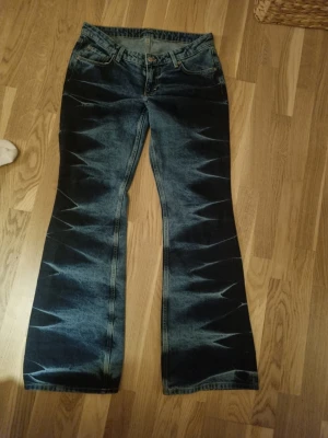Blå bootcut jeans med mönster från weekday - Säljer ett par blå bootcut jeans med unikt blekt zigzag-mönster längs benen i strl 30 i modellen nova! Jeansen har låg midja och klassisk femficksdesign. Materialet är jeans i bomull och passformen är loose med breda ben. Perfekta för dig som vill sticka ut med en cool retrostil. Köpte de på plick men var lite för stora för mig! Kom jättegärna med prisförslag, vill bli av med de! Sista bilden är dens jag köpte ifrån!