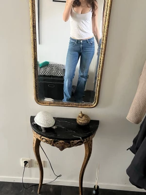 90s boot - Säljer ett par klassiska blå jeans med rak passform och låg midja. Jeansen har fem fickor och stängs med dragkedja och knapp. Perfekta till vardags och lätta att matcha med olika stilar. Materialet är denim i bomull.