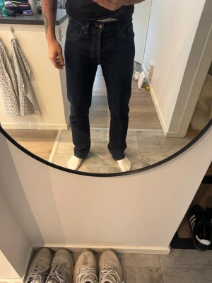 Mörkblå raka jeans från Nudie - Mörkblå Nudie Jeans ”Average Joe”. Tvättade endast en gång. Storlek 30/32. Ganska stor benöppning, sitter lite bootcut. Killen på bilden är 175cm lång. Tveka inte att höra av dig om du har frågor. 
