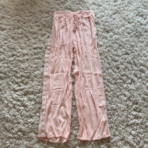 Ljusrosa vida linnebyxor med spets - Superfina ljusrosa linnebyxor med bred resår i midjan och snörning med tofsar. Vida ben och dekorativ spets längs sidorna🩷 Midjemått 30x2  cm innerbenslängden 65 cm gren 29 cm. Står storlek S fast skulle säga XXS-XS