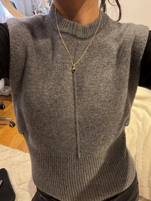 Grå stickad väst med ribbad kant - Snygg grå stickad väst med ribbad kant nedtill. 