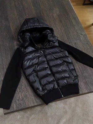 Marcél Classic 02 Hybrid Jacket - Quiltad pufferkropp, stickade ärmar, helzip, avtagbar huva, signaturguldbricka. Lapp kvar, utmärkt skick. Köp med Klarna på www.cain.se eller DM:a mig här! 🤝​​​​​​​​​​​​​​​​