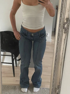 Nelly bootcut jeans med ränder  - Säljer ett par blå bootcut jeans i washed vintage färg med låg midja och dekorativa sömmar som bildar ränder framtill. Jeansen har fickor med lock och bälteshällor i vintage modell. Ifrån Nelly. Superstretch i material så passar definitivt även 40. Framhäver formerna med en figurnära passform som passar allt från 36-40 tack vare stretchen. Först till kvarn. Säljs inte längre hos Nelly. Pris kan diskuteras. 