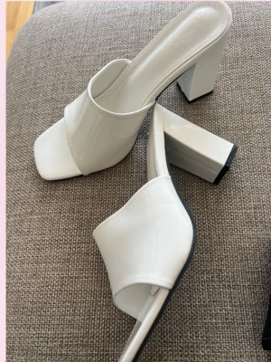 Vita pumps  - 💕Stilrena vita pumps med bred chunky klack och fyrkantig öppen tå. Skorna har en bred rem över foten och är gjorda i ett glansigt material Perfekta för dig som gillar minimalistisk och trendig design.💓