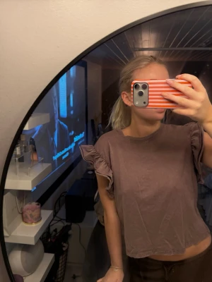 Lila volangtopp från Zara - Säljer en lila topp från Zara med volangdetaljer på ärmarna. Toppen har en croppad passform och är tillverkad i mjuk bomull, perfekt för en avslappnad och trendig look.