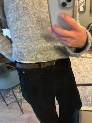 Mörkbrunt vintage bälte - Snyggt mörkbrunt bälte i mocka med klassiskt metallspänne. Perfekt accessoar för att lyfta din outfit och passar till både jeans och kostymbyxor. Enkel design utan mönster och med flera hål för justerbar passform.