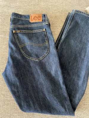 Lee Daren Zip Fly jeans blå W32 L34 - Säljer ett par klassiska blå jeans från Lee, modell Daren Zip Fly. Jeansen har normal passform, dragkedjegylf och snygga kontrastsömmar. Storlek: 32/34. Nypris: 999kr, mitt pris 449kr. 