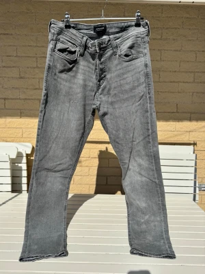 Gråsvarta raka jeans Intelligence - Jack & Jones Jeans med rak passform och klassisk femficksdesign. Intelligence i 32/32. Jeansen har en snygg tvättad look. 