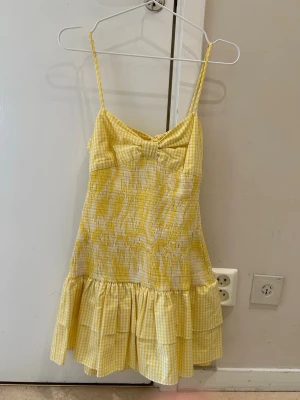  Ny Gul rutig klänning från Zara - Söt gul och vit rutig klänning från Zara med smala axelband, rosett framtill och volangkant nertill. Klänningen är kort och har en lätt och somrig känsla, perfekt för varma dagar. Egna bilder på annonsen 