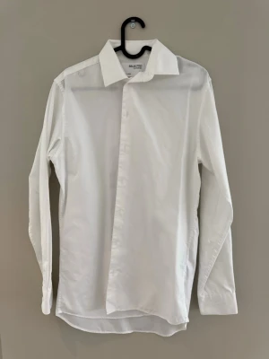 Vit klassisk skjorta från Selected Homme - Säljer en stilren vit skjorta från Selected Homme. Skjortan har lång ärm, klassisk krage och knappar framtill. Tillverkad i mjuk bomull som känns skön mot huden. Perfekt för dig som gillar en clean och enkel look.