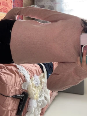 Ljusrosa stickad tröja - Mysig ljusrosa stickad tröja med rund halsringning och långa ärmar. Tröjan har en enkel och stilren design med ribbstickade muddar vid ärmslut och nederkant. Perfekt för lager-på-lager och passar till det mesta.