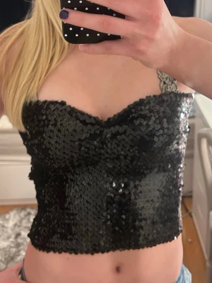 Svart fest paljettopp  - Snygg svart topp täckt med paljetter. Toppen har croppad passform och smickrande v-ringning. Perfekt för dig som vill sticka ut och addera lite extra bling till din outfit. Har inga skador eller defekter❤️Perfekt festtopp🫶