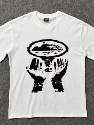 Vit t-shirt med grafiskt tryck - Vit t-shirt med ett stort svart grafiskt tryck på framsidan som föreställer två händer och ett abstrakt motiv ovanför. Klassisk rund hals och korta ärmar. Perfekt för dig som gillar unik och konstnärlig stil.