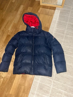 Mörkblå pufferjacka från Tommy Hilfiger - 55 cm lång och 49 cm bredd fick den i present från en kusin i jul helt ny, men har aldrig passat så helt oanvänd rekommenderar om du är 160-172. Storlek S-Xs.