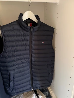 Svart väst Tommy Hilfiger - Den är helt ny, använd 1-2 gånger, fick den i present med den är för liten. Perfekt för våren och även nu till sommarkvällarna. Sänker pris vid snabb affär! 