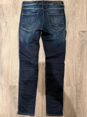 Replay Anbass Hyperflex Mörkblå Jeans W29/L32 Slim Fit - Replay Anbass Hyperflex mörkblå jeans i stretchigt och bekvämt material, slim fit modell som sitter bra och funkar till allt, storlek W29/L32, midja 38 cm, ytterbenslängd 103 cm, benöppning 15 cm, modellen är 185cm & väger 65kg, i fint skick.