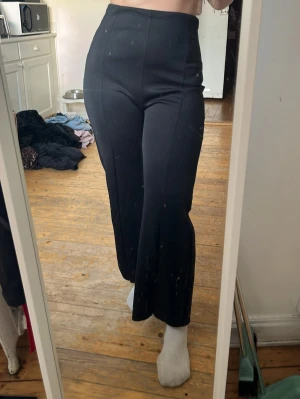 Svarta vida mjukisbyxor med hög midja - Säljer ett par svarta mjukisbyxor med hög midja och utsvängda ben. Byxorna har en slät och stilren design utan synliga fickor eller loggor. Perfekta för en chill och avslappnad look. Materialet är mjukt och stretchigt för extra komfort.