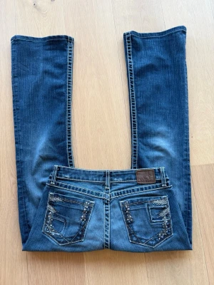 Blå jeans med broderade bakfickor - Snygga blå jeans från BKC Denim med raka/bootcut ben. Storlek 27x33 skulle säga M. Köpta second hand för 799kr säljer för 300kr