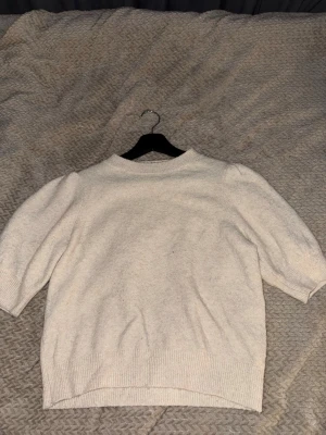 Vit stickad tröja från Vero Moda - Mysig vit stickad tröja från Vero Moda med rund halsringning och halvlånga ärmar. Tröjan har ribbade muddar vid ärmslut och nederkant, samt en något lösare passform. Perfekt för lager på lager och enkel att matcha.