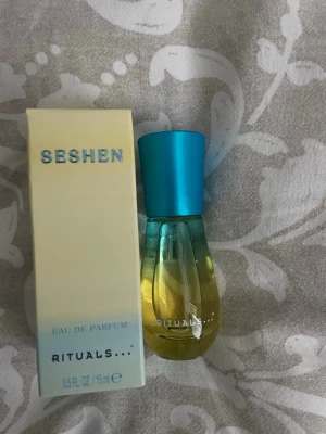 Rituals Seshen Eau de Parfum 15ml - Fräsch parfym från Rituals i doften Seshen. Flaskan är genomskinlig med gul vätska och har ett stilrent blått lock. Kommer i originalförpackning med ljusblå och vit design. Perfekt storlek på 15 ml att ha med i väskan.