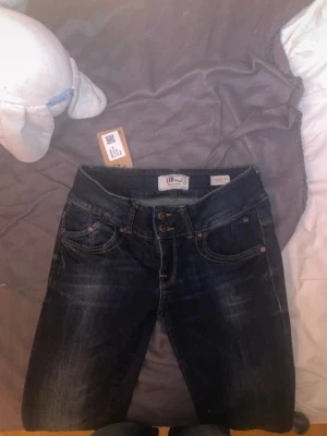 Mörkblå jeans från LTB - Snygga mörkblå jeans från LTB med klassisk femficksmodell och dubbla knappar i midjan. Jeansen har en lätt tvättad look och kontrastsömmar som ger en cool touch. Perfekta för dig som gillar en avslappnad men trendig stil.