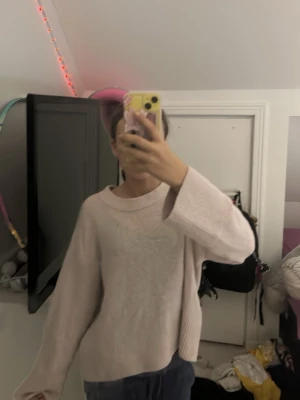 Ljusrosa stickad tröja - Mysig ljusrosa stickad tröja med breda ärmar och avslappnad passform. Tröjan har en rund halsringning och är perfekt för lager på lager. Passar dig som gillar en enkel men trendig stil.