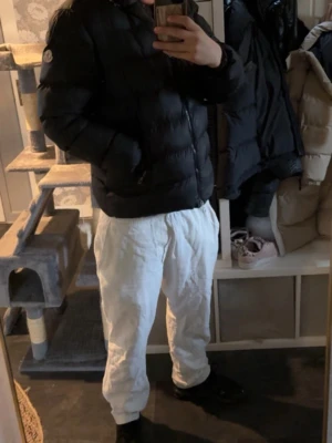 Svart pufferjacka från Moncler - Säljer en svart pufferjacka från Moncler med klassisk quiltad design och hög krage. Jackan har dragkedja framtill, två sidofickor och Moncler-logga på ärmen. Perfekt för kalla vinterdagar och riktigt snygg till streetwear-stilen. (OBS Pris kan sänkas.)