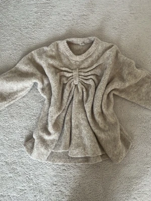 Stickad tröja med rosettdetalj - En stickad tröja med rosettdetalj fram i ull från Arket💕bara använd 1 gång och i väldigt bra skick💕storlek xs/s men är lite oversized så sitter mer som en s/m på