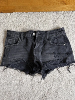 Svarta denimshorts med fransig kant - Snygga svarta jeansshorts med fransig och sliten kant samt slitningar framtill! 