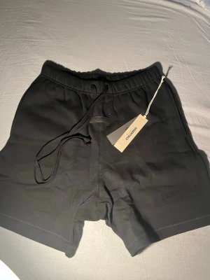 Svarta essentials shorts - Svarta  essentials essentials med elastisk midja och snörning. Tillverkade i mjukt material som passar perfekt för träning eller chill. Klassisk och enkel design utan synliga mönster, med diskret logga på benet.