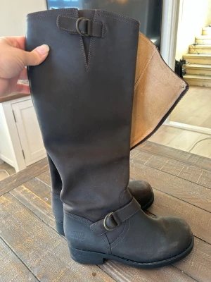 Svarta höga läderstövlar Johnny Bulls, 38 - Snygga bruna höga stövlar från Johnny Bulls i äkta läder. Klassisk tidlös modell med spänne upptill och vid ankeln, grov sula och dragkedja på insidan. Använda någon enstaka gång, som nya.