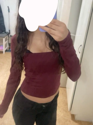 Vinröd långärmad  - Säljer en vinröd långärmad croppad topp med fyrkantig halsringning. Toppens passform är tight och den är tillverkad i ett mjukt syntetmaterial. Perfekt för dig som gillar stilrena och trendiga plagg.