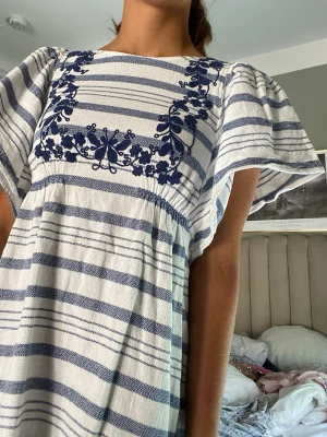 Randig blåvit Zara klänning med broderi - ❣️Gammal bildtagning❣️Säljer en söt blåvit randig klänning med broderade blommor och fjärilar vid halsen från Zara. Klänningen har vida korta ärmar och en lös passform som ger en avslappnad känsla. Perfekt för varma dagar och har en bohemisk touch. Passar en Xs!! Bara att be om fler bilder vid önskemål🥰
