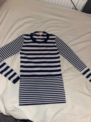 Randig ribbad långärmad topp - Snygg långärmad topp med marinblå och vita ränder. Ribbad struktur som ger en tight passform och markerar siluetten. Perfekt att styla med jeans eller kjol för en fräsch look.