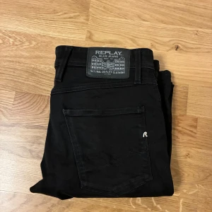 Svarta jeans från Replay - Snygga svarta jeans från Replay med klassisk femficksdesign och diskret logga på bakfickan. Jeansen har raka ben och är tillverkade i ett mjukt bomullsmaterial med lite stretch för extra komfort. Perfekta för en stilren och avslappnad look.