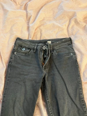 Svarta jeans med broderade fickor - Snygga svarta jeans med utsvängda ben och coola broderade bakfickor. Klassisk femficksmodell med knapp- och dragkedjegylf. Jeansen har detaljerade ficklock bak med knappar och är tillverkade i denim. Byxorna är i barnstrorlek 164 men passar nog en xxs, xs som är under 165cm (jag är 168 cm) finns en liten fläck(se bild 3) men den går bort i tvätten då det bara är lera