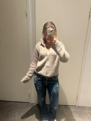 Blå bootcut jeans med glitterdetaljer - Säljer ett par blå bootcut jeans med slitningar och glitterdetaljer i bakfickorna! Jeansen har klassisk femficksdesign och kontrastsömmar. Jeansen är vintage, så ingen annan kommer att ha likadana jeans som du! I ena byxbenet finns lite slitage, men det påverkar inte utseendet. Perfekt för dig som gillar en stockholmstil och trendig look!🥰💕