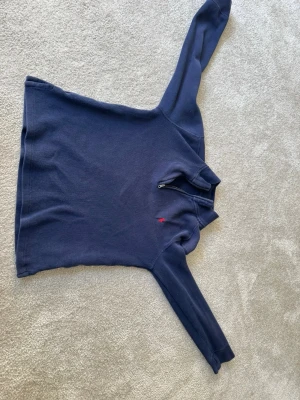 Mörkblå half zip tröja från Polo Ralph Lauren - Säljer en stilren mörkblå tröja från Polo Ralph Lauren med en liten röd logga på bröstet. Tröjan har en dragkedja vid halsen och långa ärmar. Perfekt för en avslappnad och snygg look. XS. Finns en reva i tröjan.
