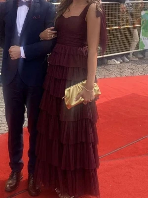 Vinröd långklänning med volanger - Vinröd långklänning med flera lager av volanger och breda axelband. Perfekt balklänning! Som ny, köpt för 2200 ink tull, ge prisförslag! I den vanliga längden, inte petit, går hela vägen ner för mig som är 174! 